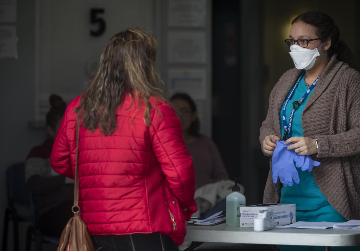 A medical assistant checks people's temperatures outside a clinic that supports victims of domestic violence.