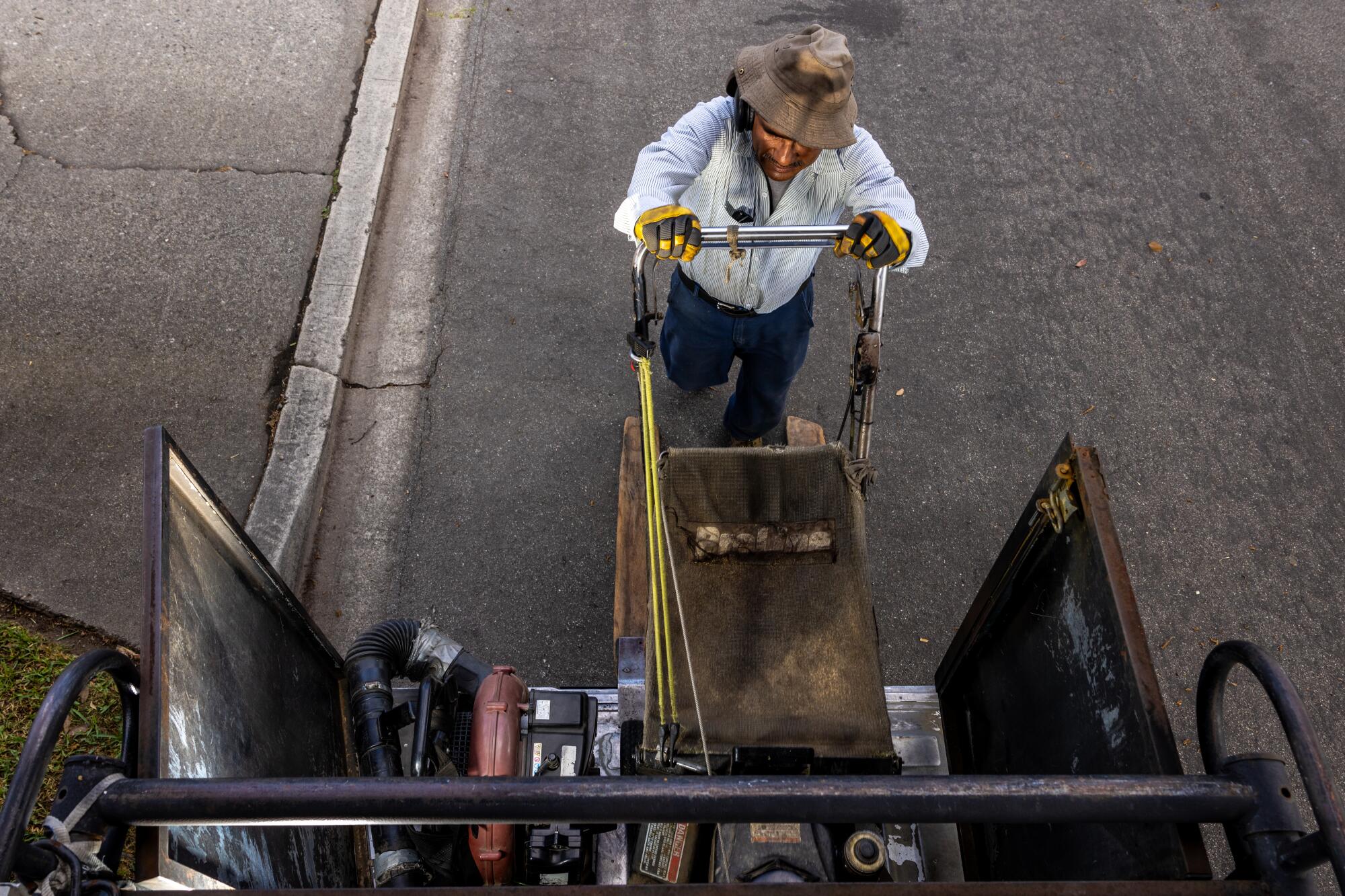 Alejandro Medel, who owns a landscaping business, loads a lawn mower.