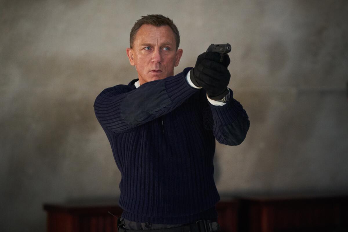 Daniel Craig as James Bond points a gun 