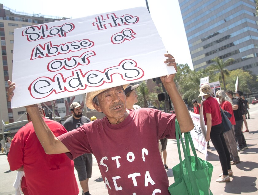 A demonstrator holds a sign that says, "Stop the Abuse of our Elders"