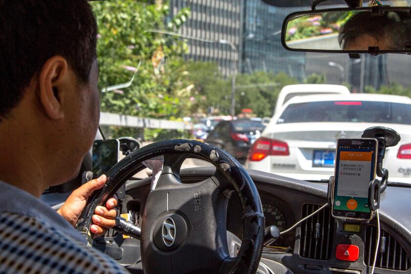 A taxi driver uses the Didi Dacha app.