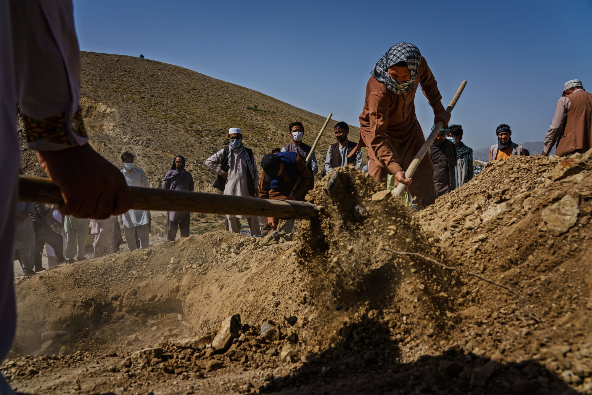 People wait as others dig a grave with shovels.