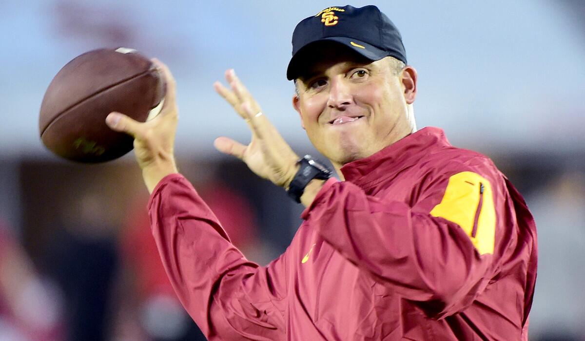 Interim coach Clay Helton throws as his team warms up before the game against Arkansas State at the Los Angeles Coliseum on Sept. 5.