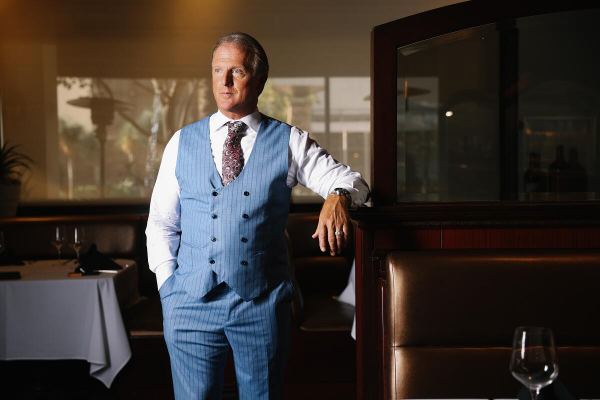 A man in a shirt, tie and suit vest standing in a restaurant.