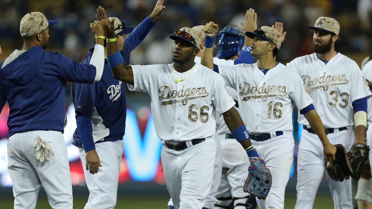 Dodgers teammates celebrate following their 4-3 win over the Cincinnati Reds at Dodger Stadium on Monday.