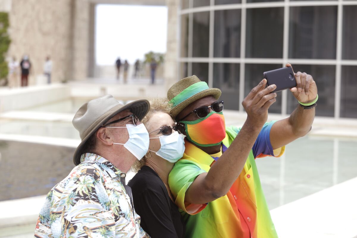 Three people wearing masks take a selfie outside the Getty Center