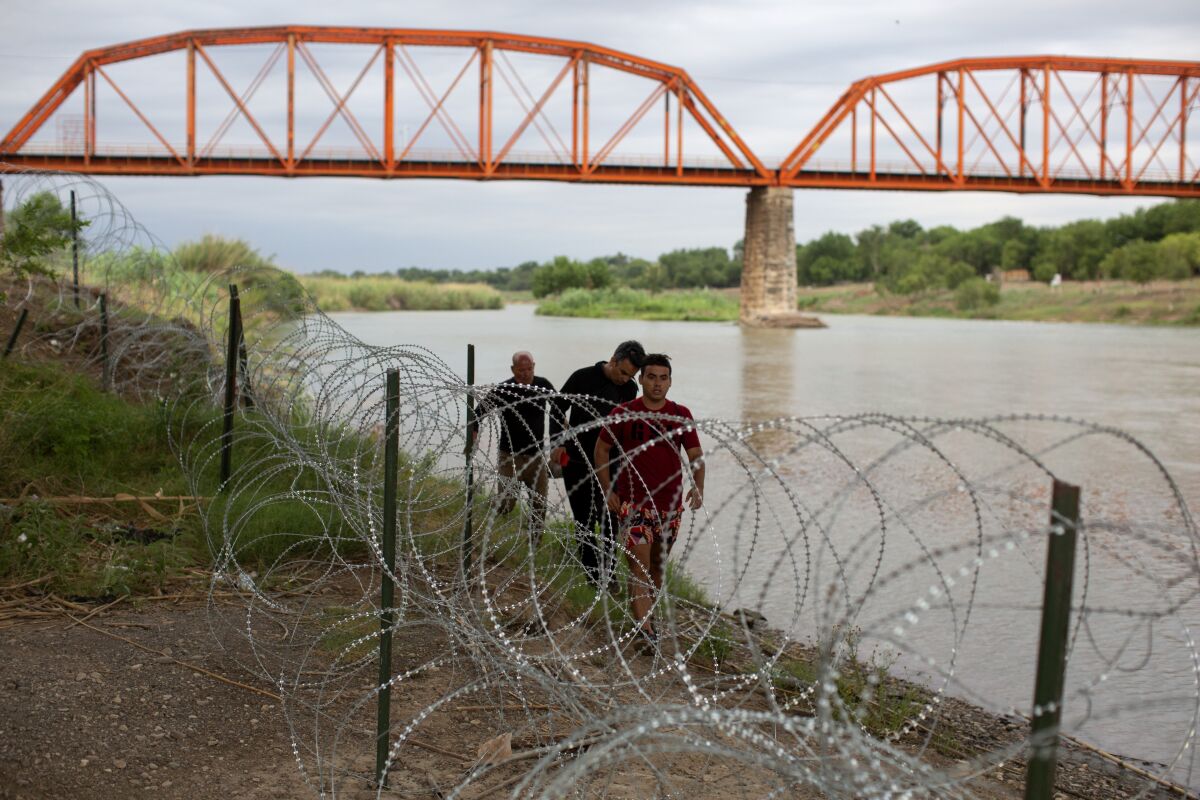 Three migrants from Cuba arrive on U.S. soil after crossing the Rio Grande river in Eagle Pass, Texas, Sunday May 22, 2022. Little has changed in what has quickly become one of the busiest corridors for illegal border crossings since a federal judge blocked pandemic-related limits on seeking asylum from ending Monday. (AP Photo/Dario Lopez-Mills)