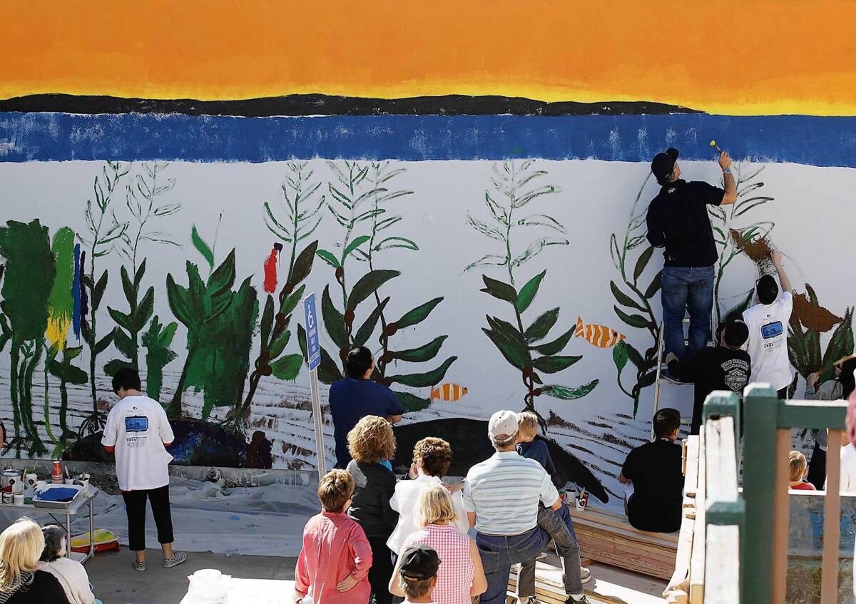 Artist Robert Wyland, on ladder, works on the mural at the Glennwood House of Laguna Beach, a former assisted living facility that will serve about 50 young adults with developmental disabilities.