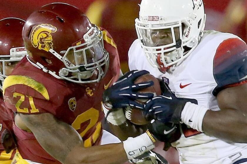 USC safety Su'a Cravens tries to strip the ball from Arizona running back Ka'Deem Carey in the fourth quarter of a Pac-12 game at the Coliseum.