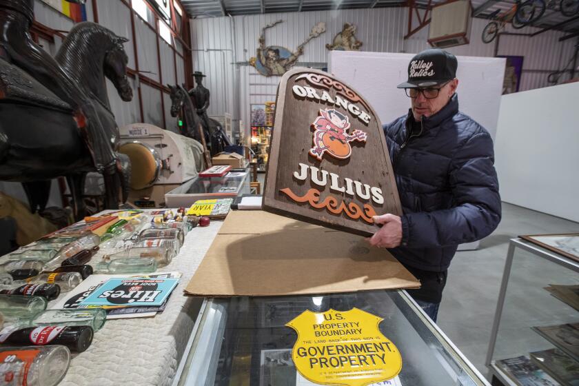 VAN NUYS, CALIF. -- THURSDAY, MARCH 19, 2020: Valley Relics Museum curator Tommy Gelinas with an original Orange Julius sign inside the museum space in Van Nuys, Calif., on March 19, 2020. (Brian van der Brug / Los Angeles Times)