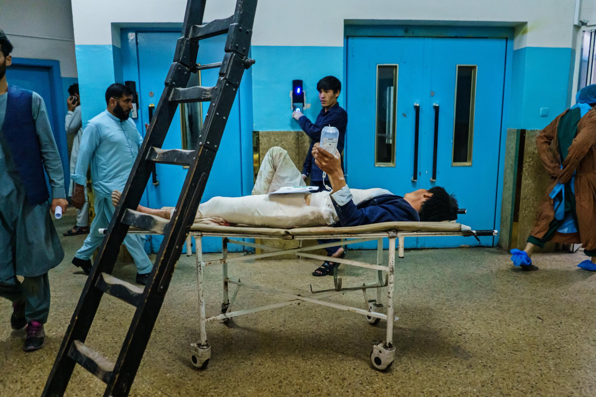A wounded patient lies on a gurney in the hallway 