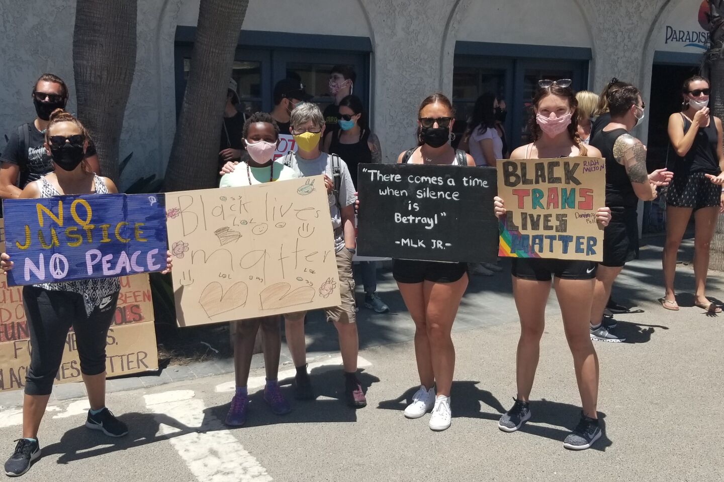 Community members stand with protest signs before the Pacific Beach Walk for Equality.