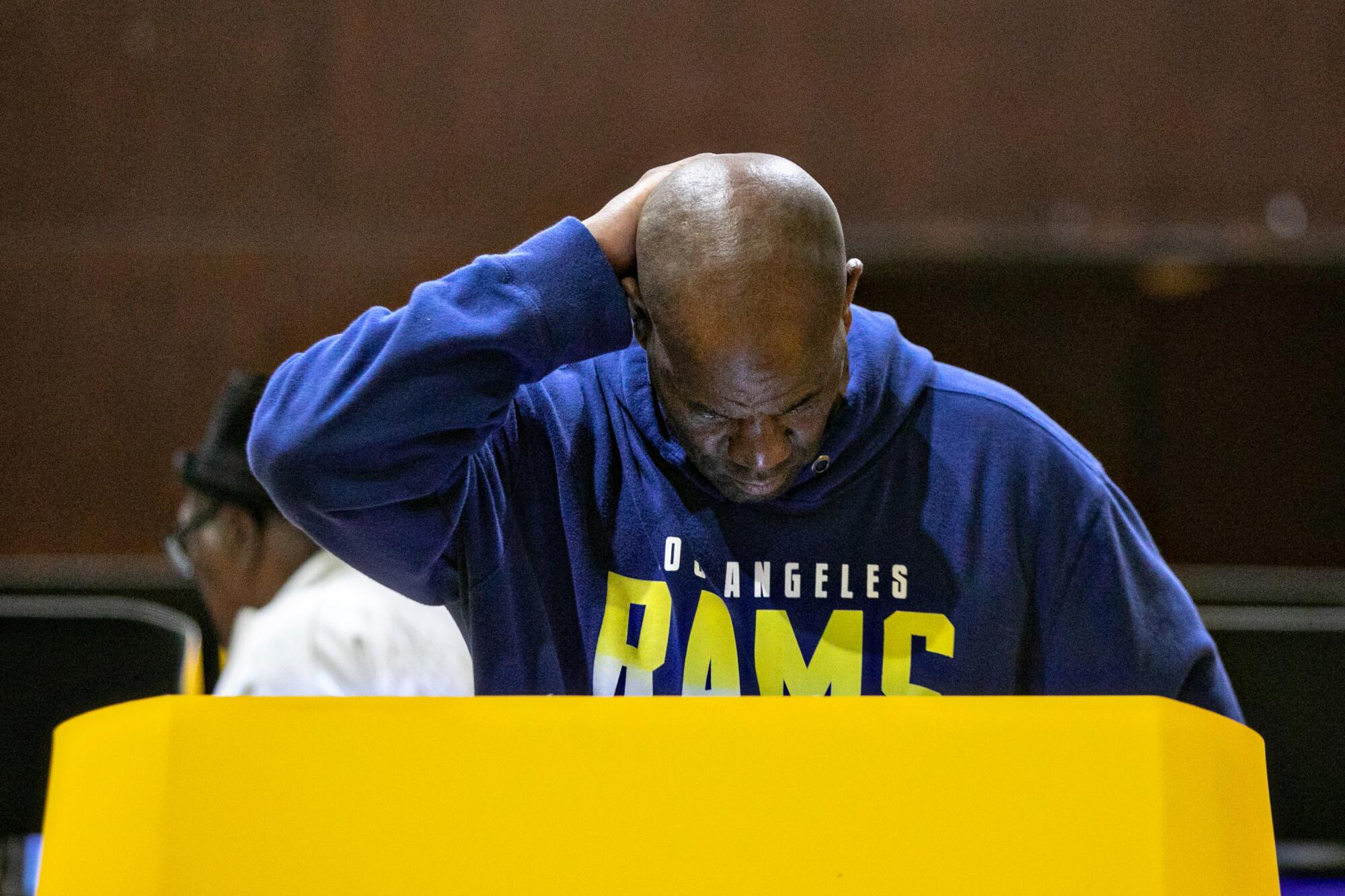 A man in a Rams sweatshirt at a voting booth
