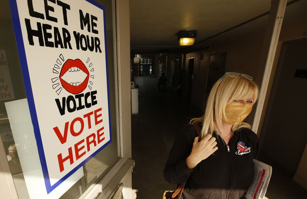 A female voter walks past a "Let me hear your voice: Vote here" sign