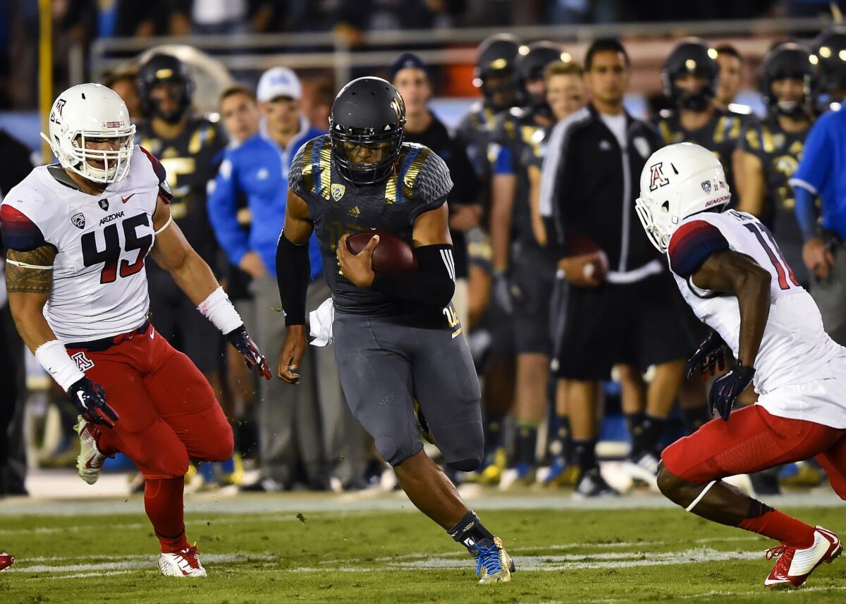 UCLA quarterback Brett Hundley, center, attempts to get by Arizona safety William Parks, right, and linebacker Derrick Turituri on Saturday.