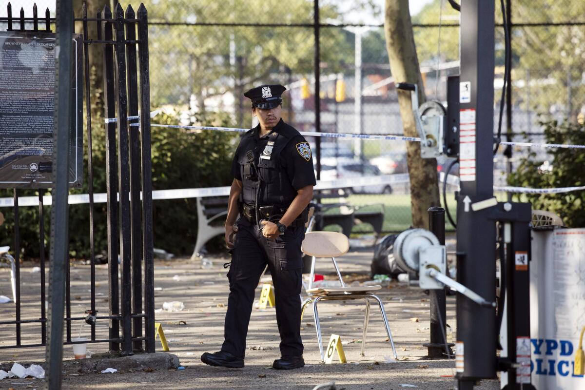 A police officer walks by yellow evidence markers at a playground in the Brownsville neighborhood in the Brooklyn borough of New York on July 28, 2019.
