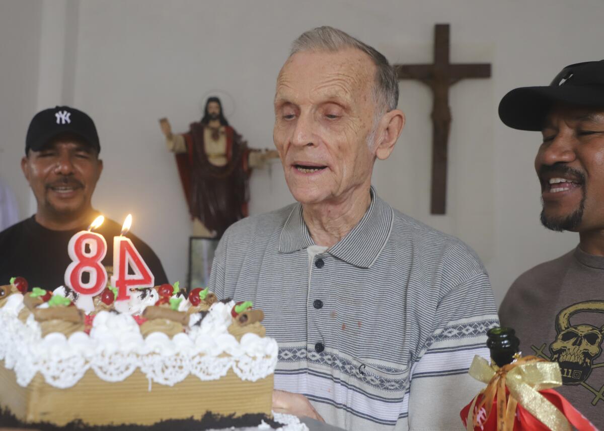 Now-defrocked Catholic priest Richard Daschbach, center, is presented a cake during his 84th birthday in Dili, East Timor, on Tuesday, Jan. 26, 2021. While he has his critics, Daschbach’s support appears deep and widespread, extending beyond Oecusse to the capital, Dili. It includes members of the political elite, including former President Xanana Gusmao _ himself an independence hero _ who attended the opening of the trial in February, and this birthday celebration. (AP Photo/Ramundos Oki)