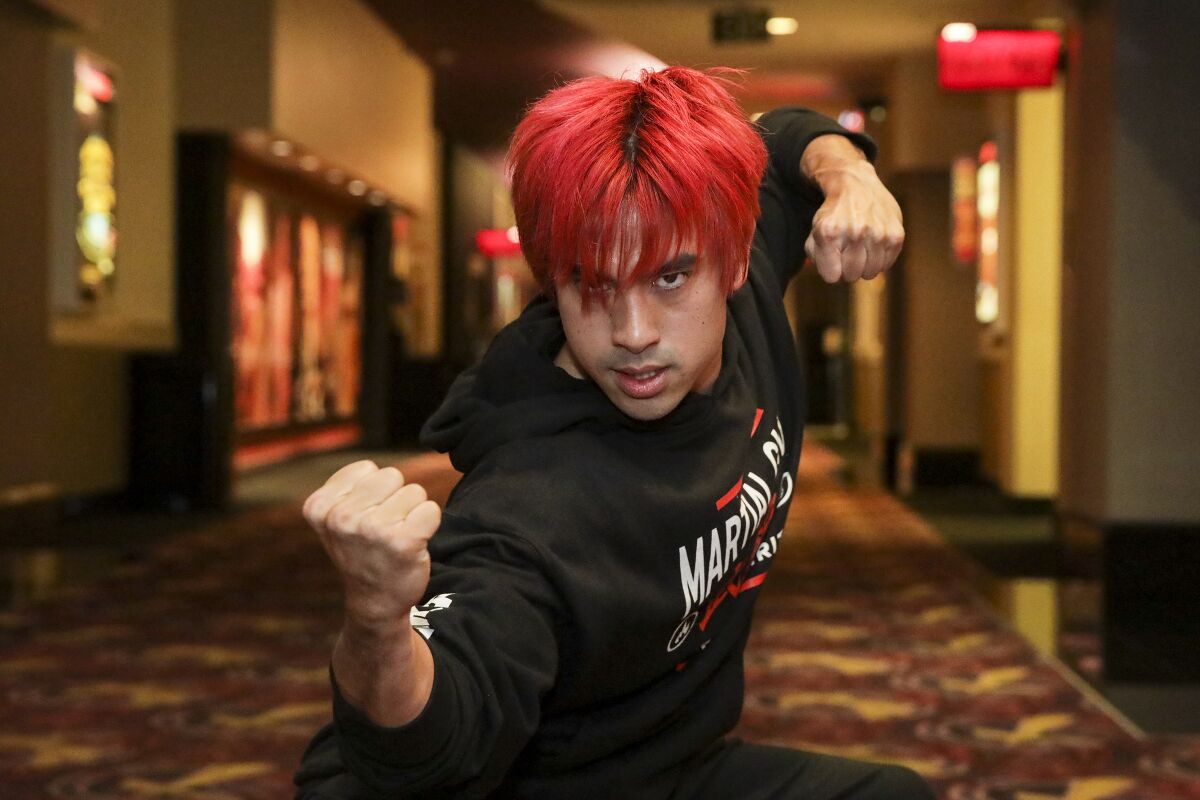 A man with red hair poses with his hands in fists.