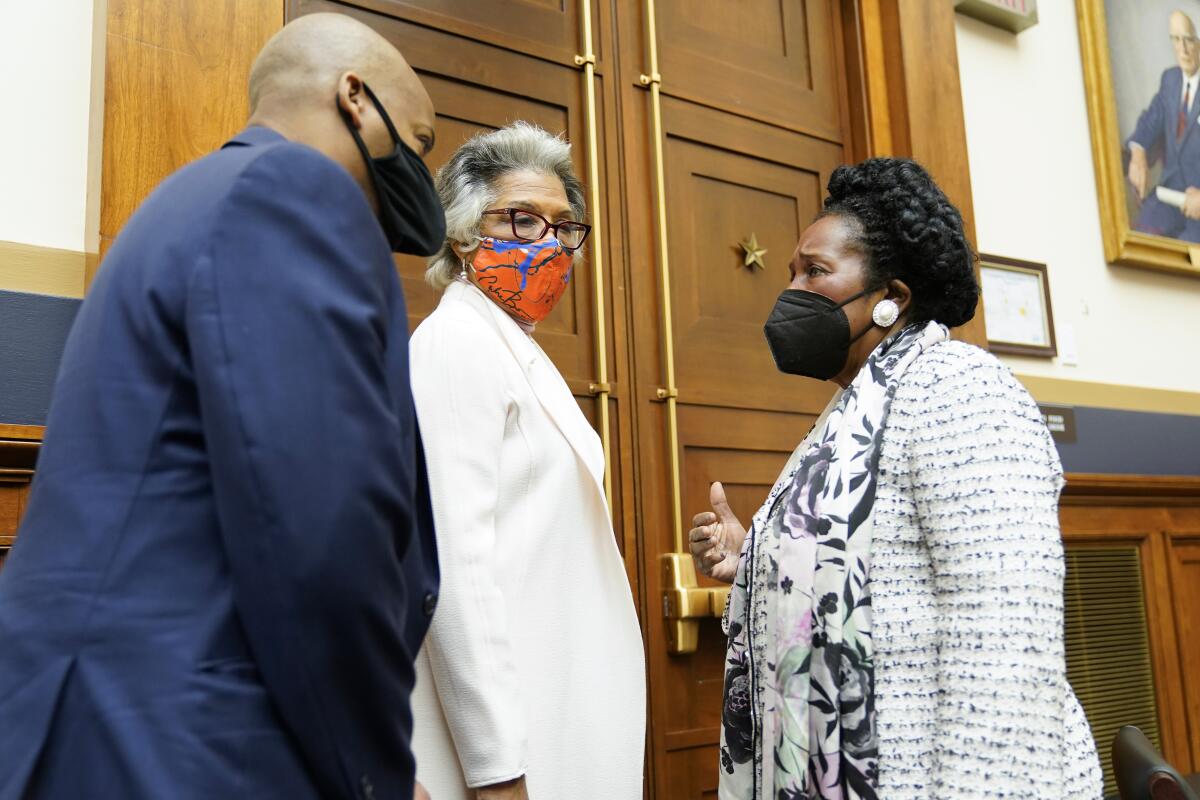 Three lawmakers in masks speak to one another