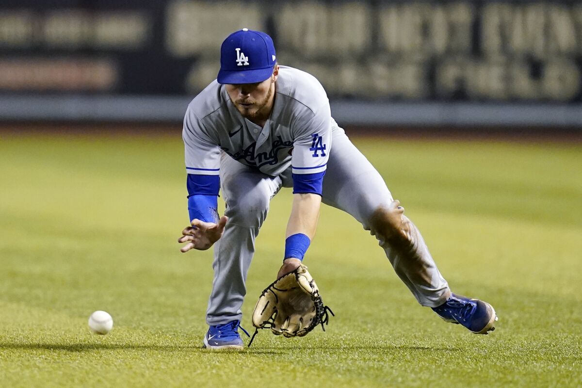 Los Angeles Dodgers left fielder Gavin Lux bends over to field a grounder 
