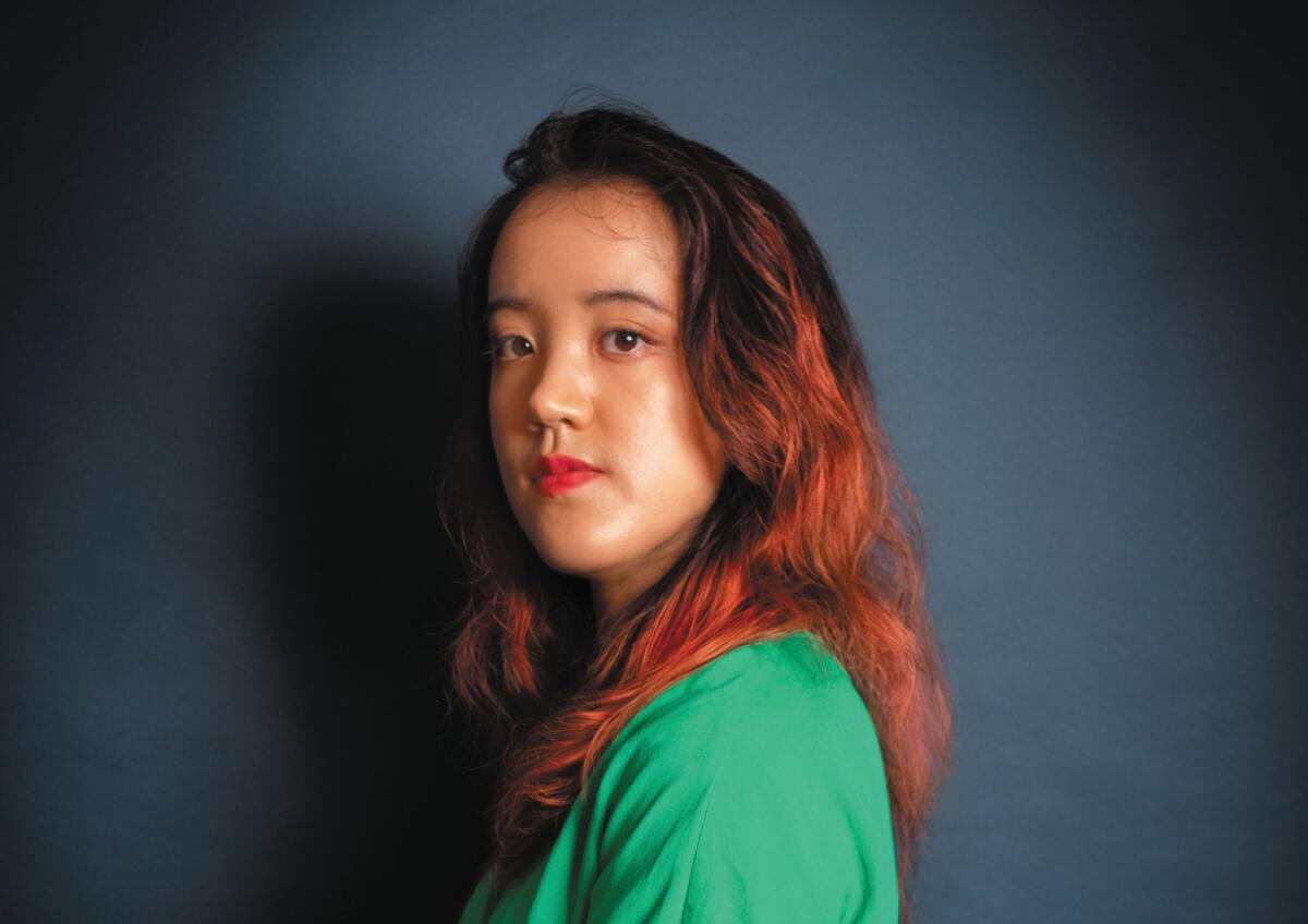 C.K. Chau, wearing a green shirt, looks over her shoulder.
