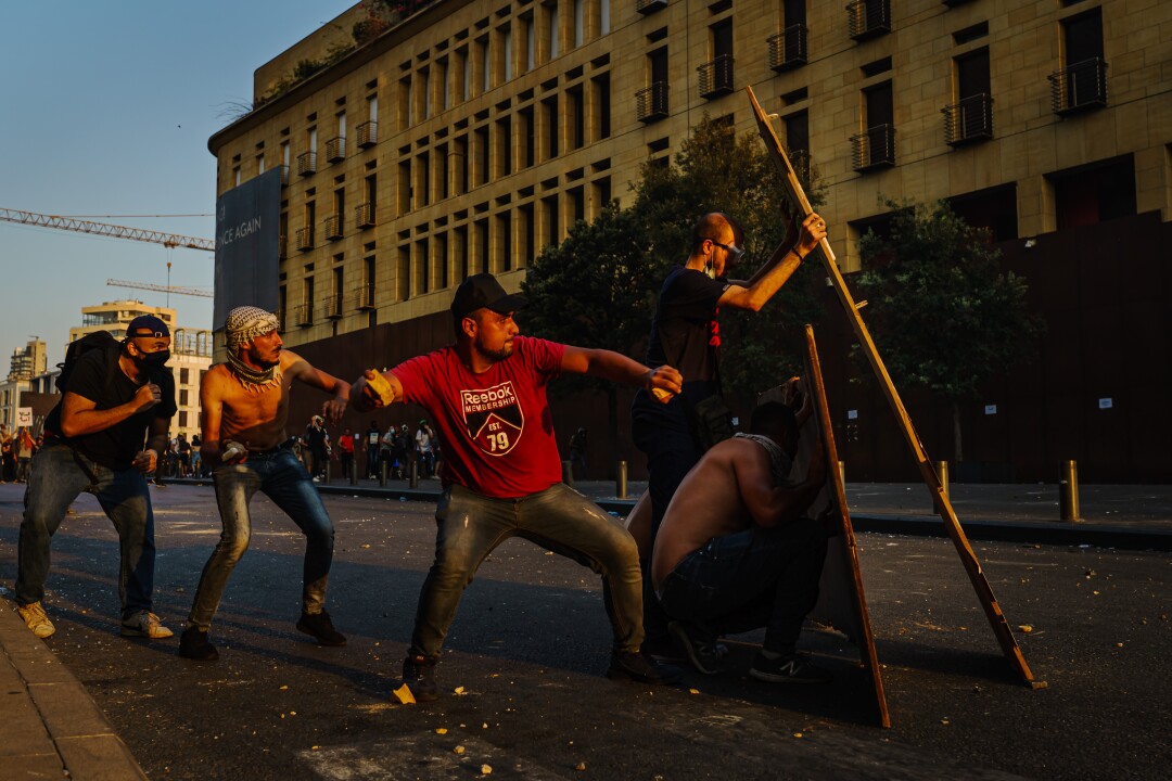 In a city street, men prepare to throw rocks.