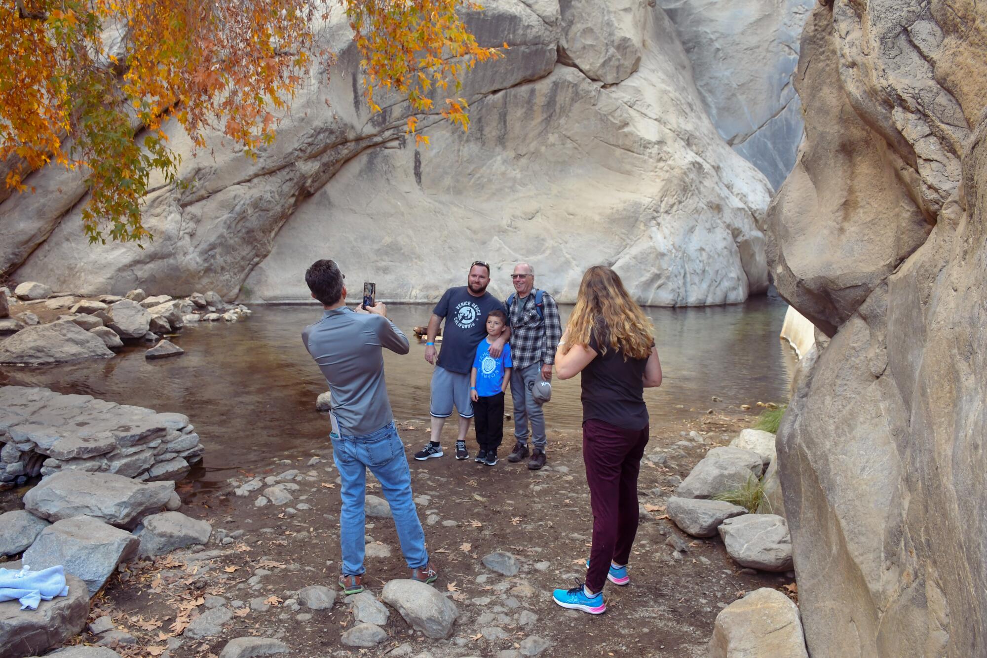 A man takes a picture of a boy, his father and his grandfather while a woman looks on.