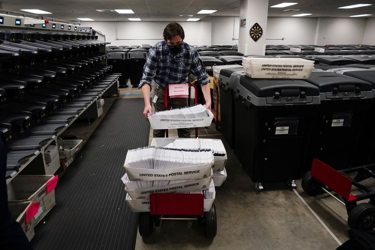 An elections worker in Chester County, Pa., stacks bins of mail-in ballots last week.