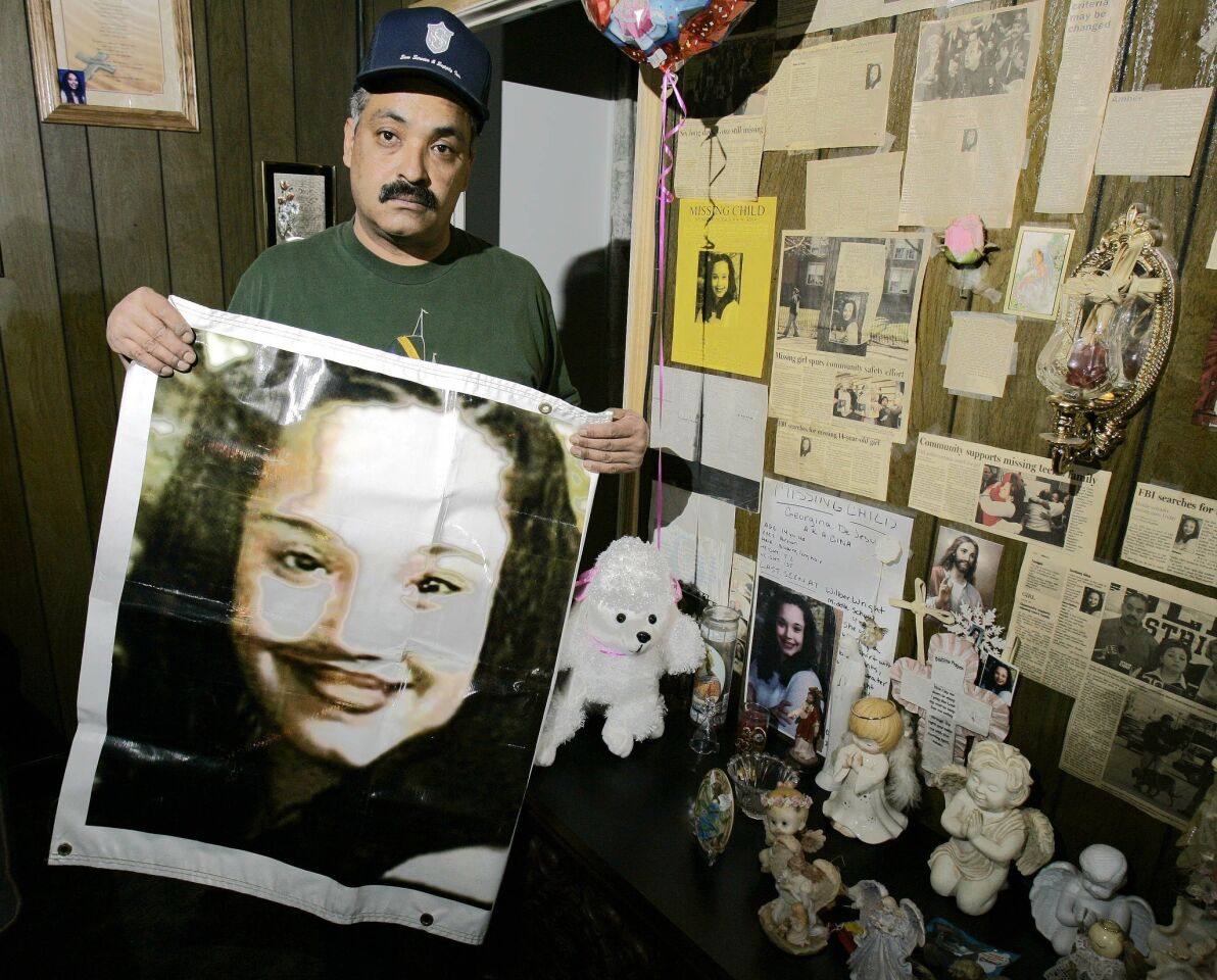 Felix DeJesus, father of Gina DeJesus, holds up an enlarged photograph of his then-14-year-old daughter next to a display in his living room shortly after she disappeared in March 2004.