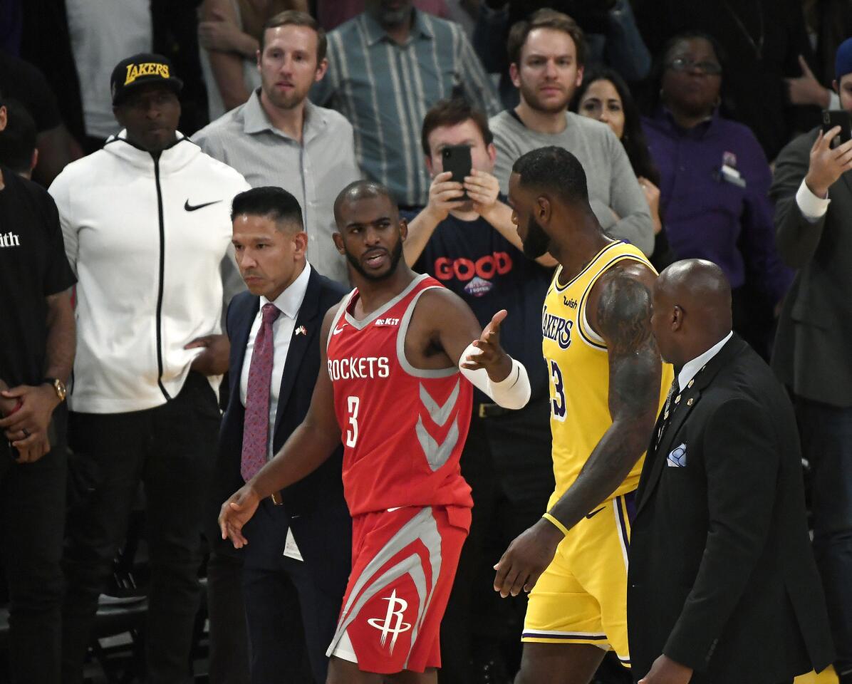 Lakers forward LeBron James talks to Rockets guard Chris Paul as he's escorted off the court after getting ejected for throwing punches.