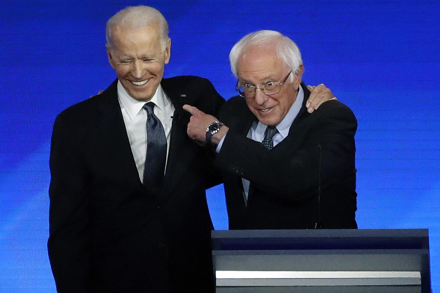 Former Vice President Joe Biden, left, embraces Sen. Bernie Sanders during the Democratic presidential primary debate on Friday in Manchester, N.H.