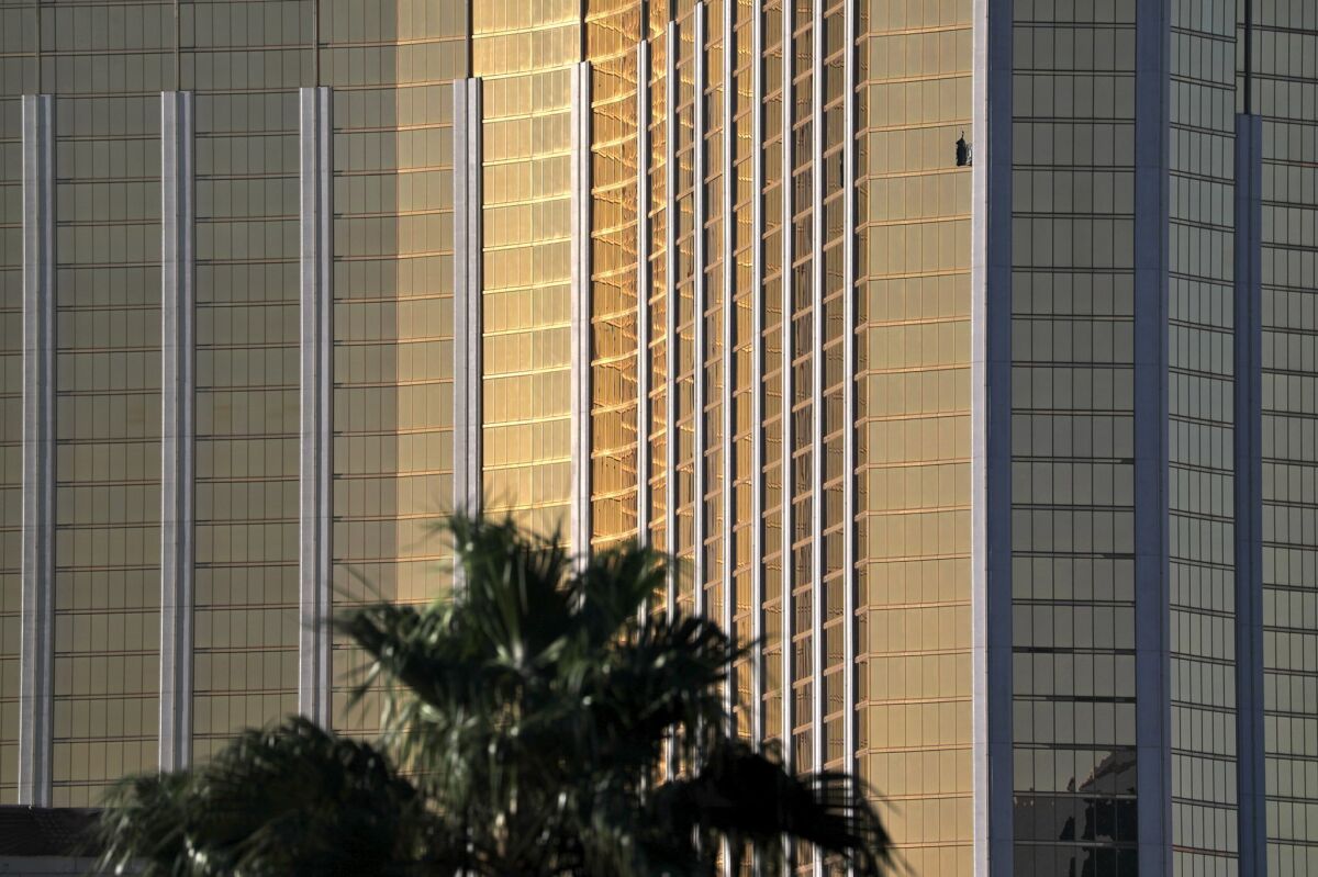 A curtain hangs out of a broken window, upper right, at Mandalay Bay on Oct. 2, 2017, the morning after a mass shooting on the Las Vegas Strip.
