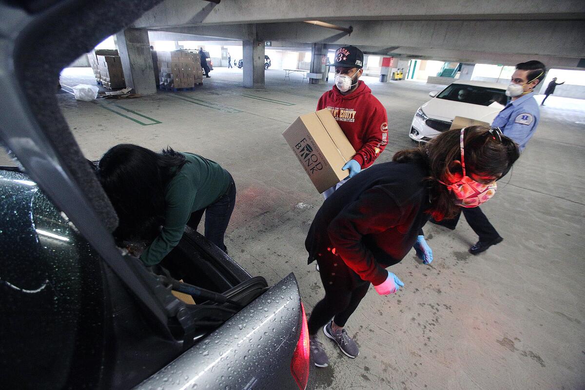 Food pantry volunteers load food into the trunk of a motorist at Glendale Community College on Tuesday, April 7, 2020.