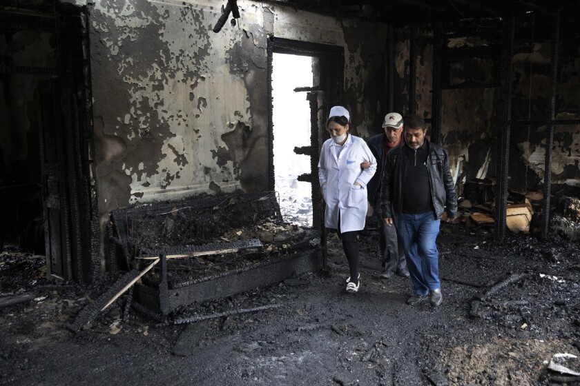 People walk inside a building destroyed by shelling