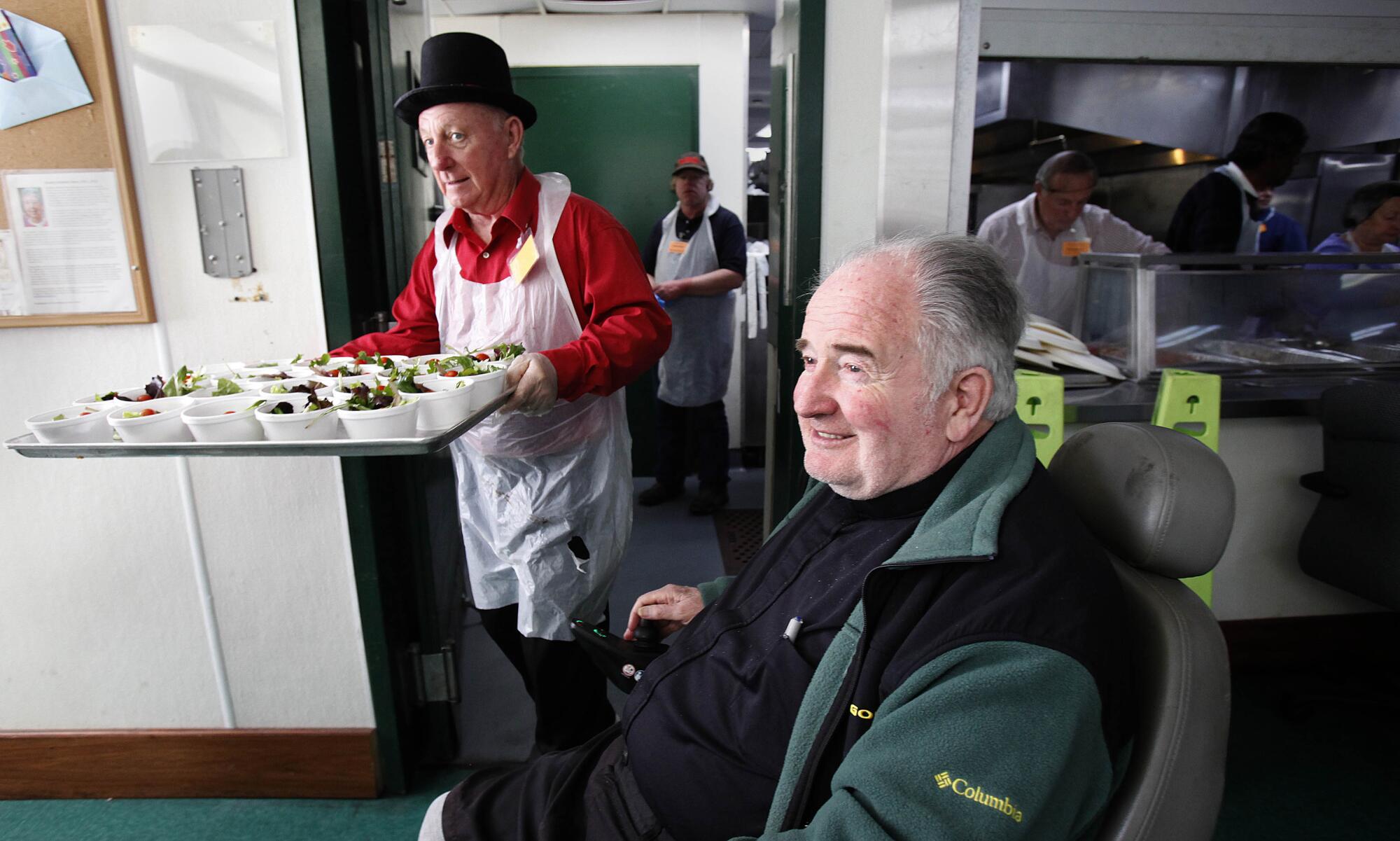 Steve Conner brings out a tray of individual salads near Father Joe Carroll