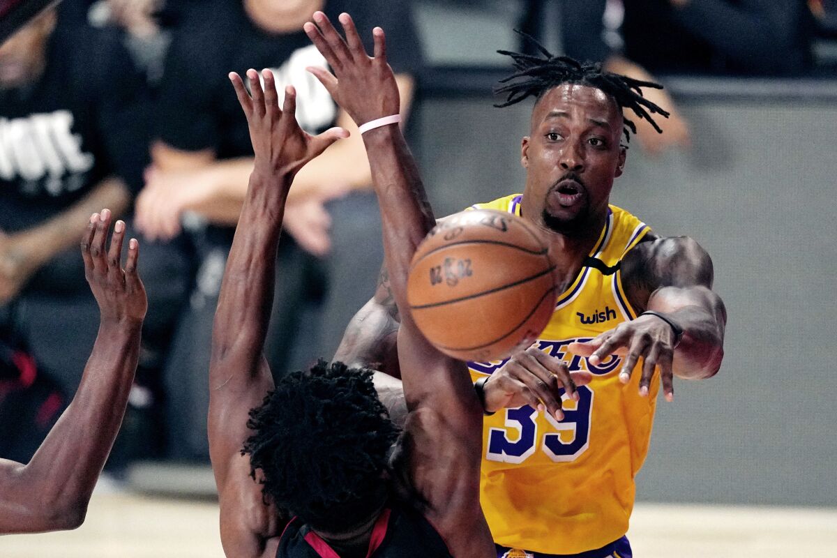 Los Angeles Lakers' Dwight Howard (39) passes the ball while pressured by the Heat defenders.