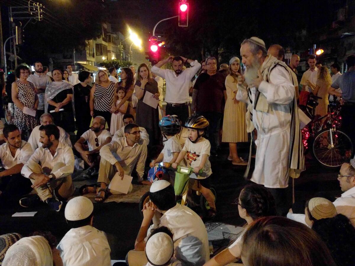 With two young cyclists looking on, Rabbi Betzalel Tsur gives a sermon about how a bike accident became an inspiration for good deeds.