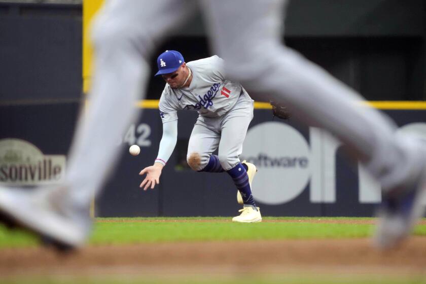 Los Angeles Dodgers shortstop Miguel Rojas (11) reaches for a ball hit by Milwaukee Brewers' William Contreras for an infield single during the eighth inning of a baseball game, Thursday, Aug. 15, 2024, in Milwaukee. (AP Photo/Kayla Wolf)