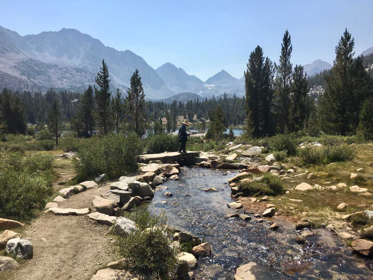 A hiker crosses a stream in the Little Lakes Valley of Inyo National Forest on Aug. 28, 2020.