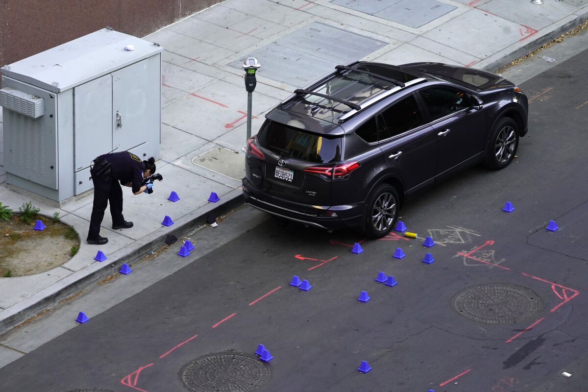 A crime scene investigator photographs evidence markers at the scene of a mass shooting In Sacramento, Calif. April 3, 2022. (AP Photo/Rich Pedroncelli)