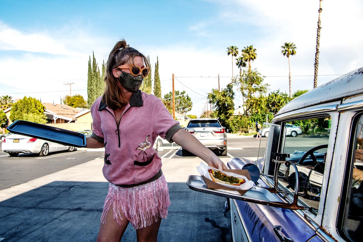 a female carhop delivers food