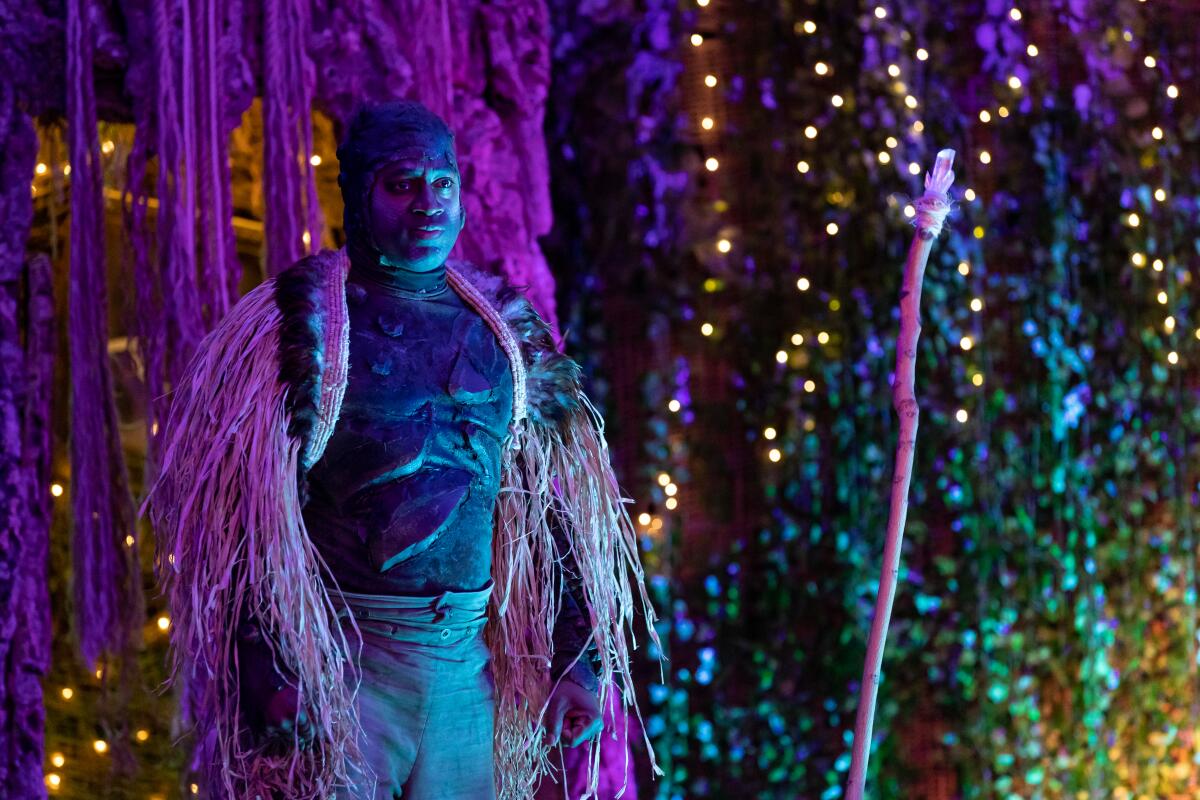 A man in costume amid colorful and sparkling lights in a scene from "The Tempest."
