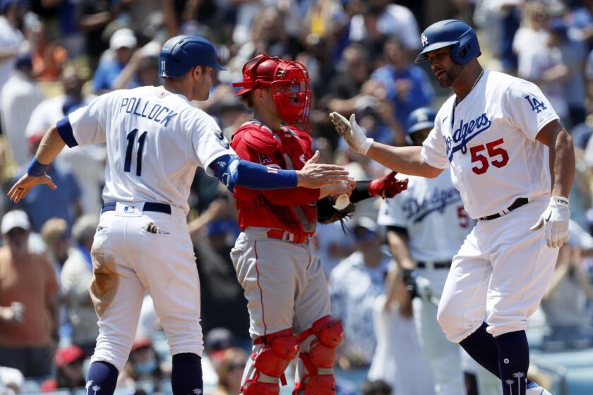 Los Angeles Dodgers' Albert Pujols, right, celebrates with AJ Pollock in front of Los Angeles Angels catcher Max Stassi, center, after hitting a two-run home run during the second inning of a baseball game in Los Angeles, Sunday, Aug. 8, 2021. (AP Photo/Alex Gallardo)