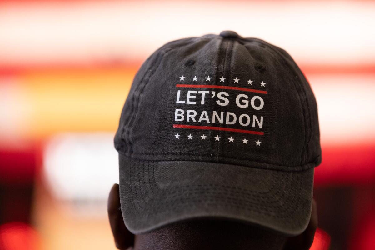 A person wears a "Let's Go Brandon" hat  backward