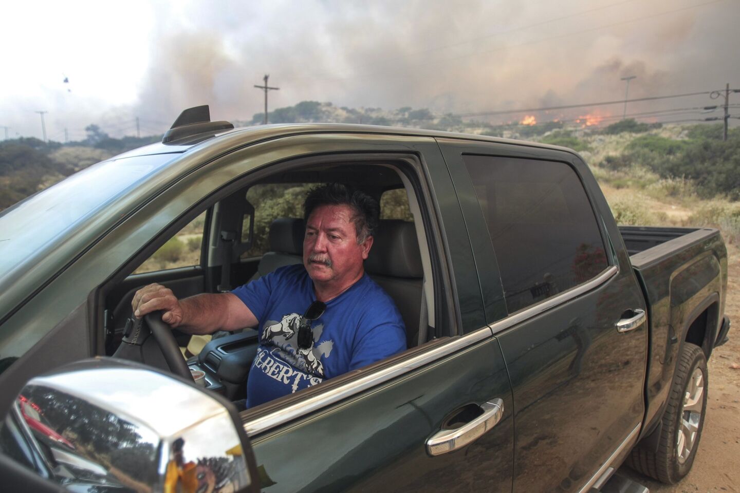 Jesus Mendoza evacuates wit his dog Sasha as flames approach his home on Highway 94 south of Potrero on Monday.