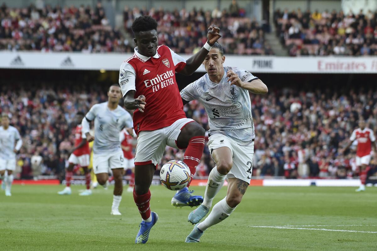 Arsenal's Bukayo Saka, left, challenges for the ball with Liverpool's Kostas Tsimikas during the English Premier League soccer match between Arsenal and Liverpool at Emirates Stadium in London, Sunday, Oct. 9, 2022. (AP Photo/Rui Vieira)