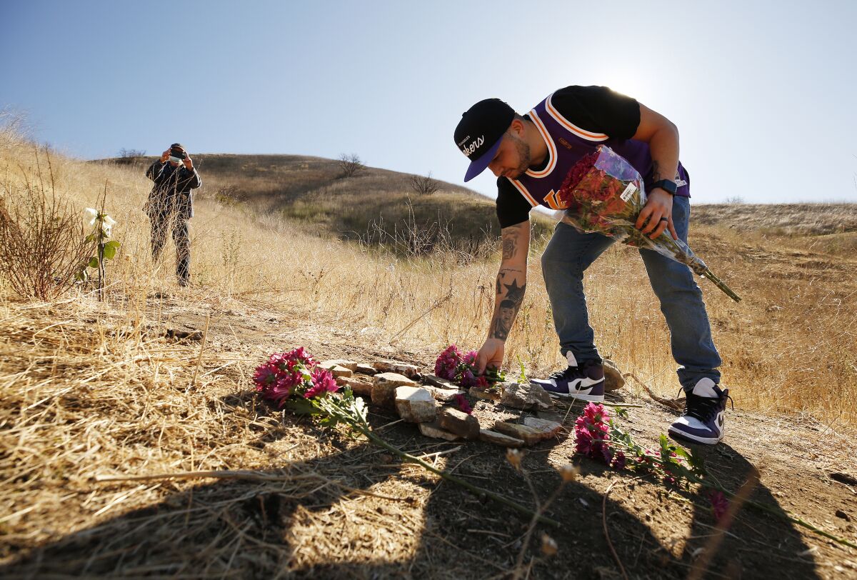 A man leaves flowers on a mountainside.