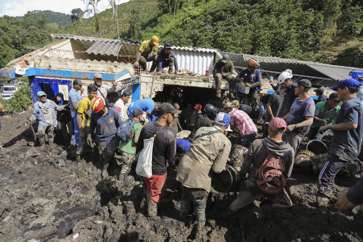 Residents and rescue workers look for survivors at a rural school buried by a landslide caused by heavy rains in Taparto, Colombia, Thursday, July 14, 2022. At least two children died when the mudslide covered the school while most pupils were at recess. (AP Photo/Jaime Saldarriaga)