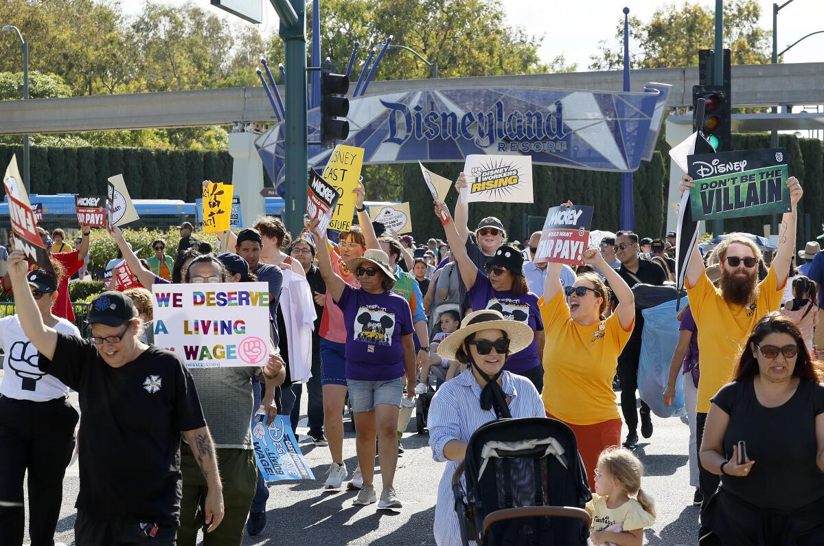 Demonstrators hold picket signs in front of the main entrance to Disneyland.