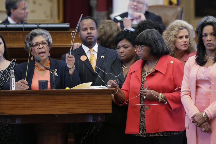 Rep. Senfronia Thompson, D-Houston, second from left, holds a coat hangar as she stands with fellow representatives while proposing an amendment to the second reading of HB 2, legislation that will restrict abortion rights, on the Texas House floor Tuesday in Austin. The Texas House is expected to vote on the bill Tuesday.